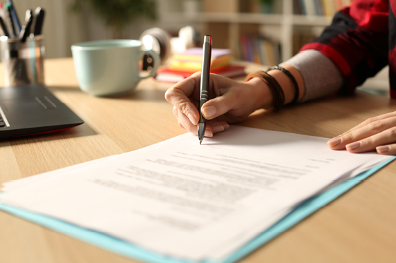 Signing a document on a wood desk